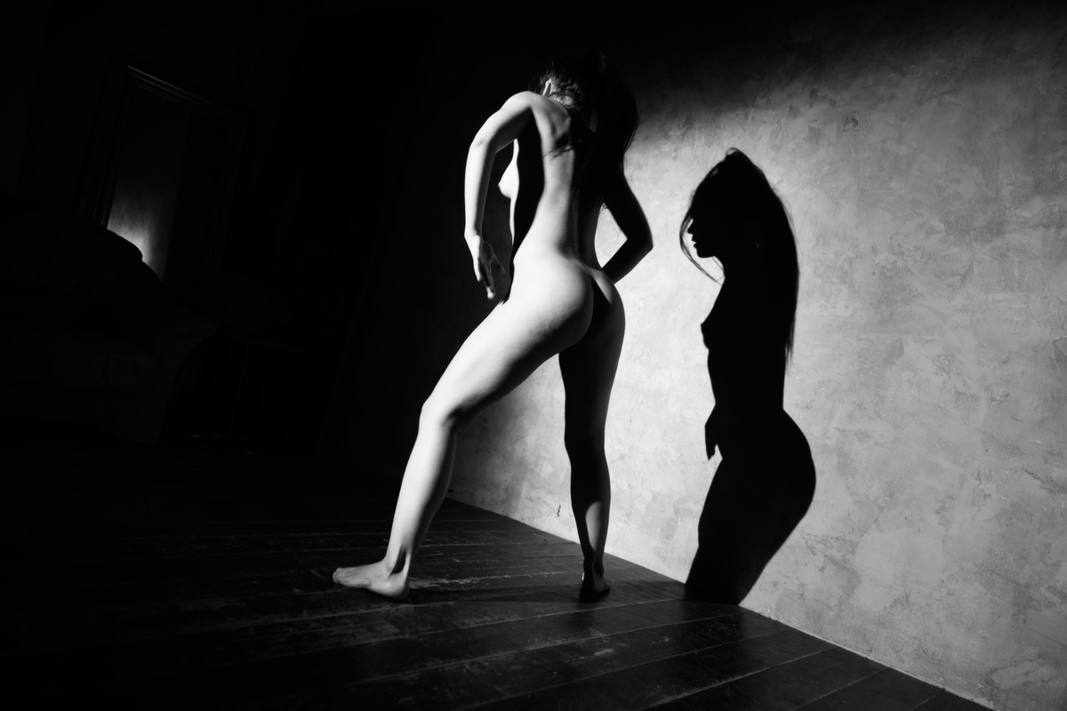Standing nude figure beside a sharply defined wall shadow.