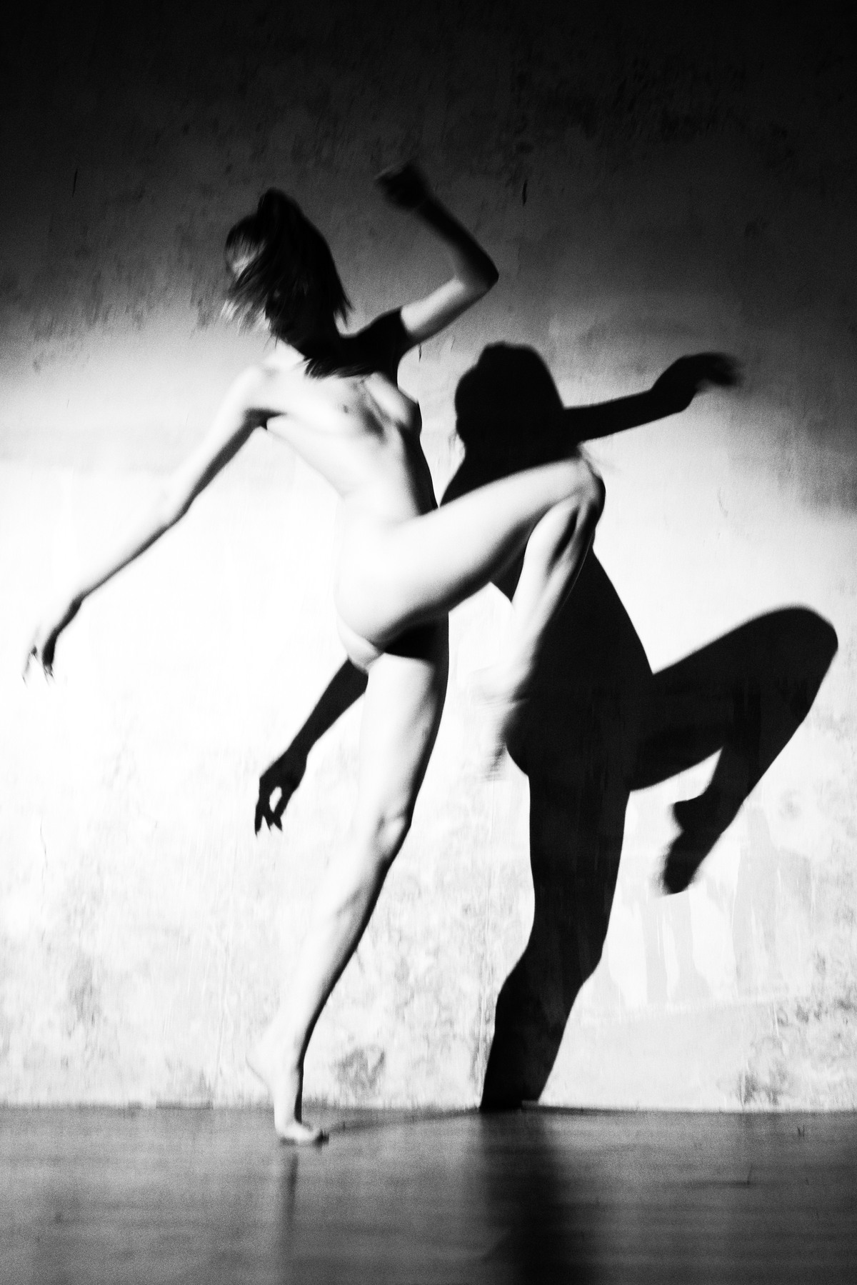 Leaping figure and sharp shadow against a bright wall.