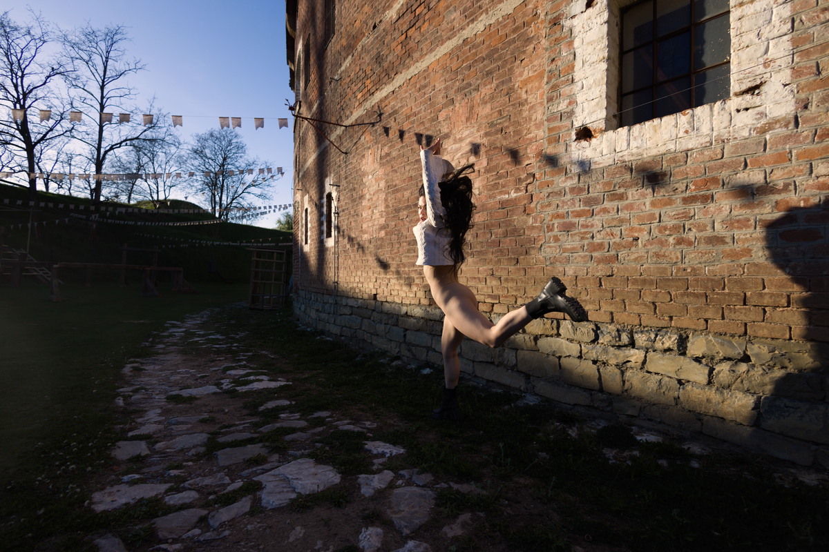 Figure leaping beside an old brick fortress.