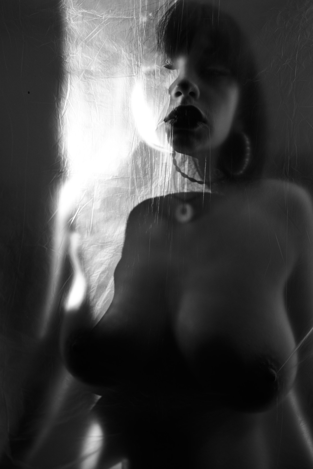 Soft-focus nude figure seen through translucent glass.