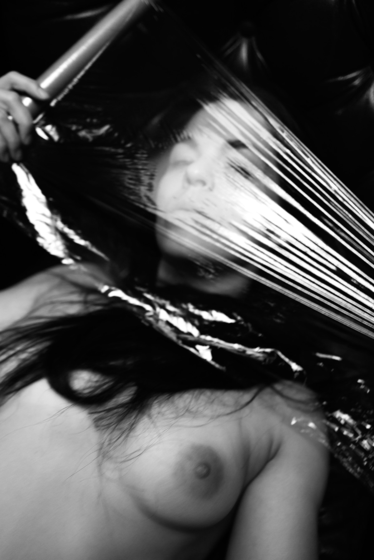 Close view of a nude figure partly obscured by stretched translucent material.