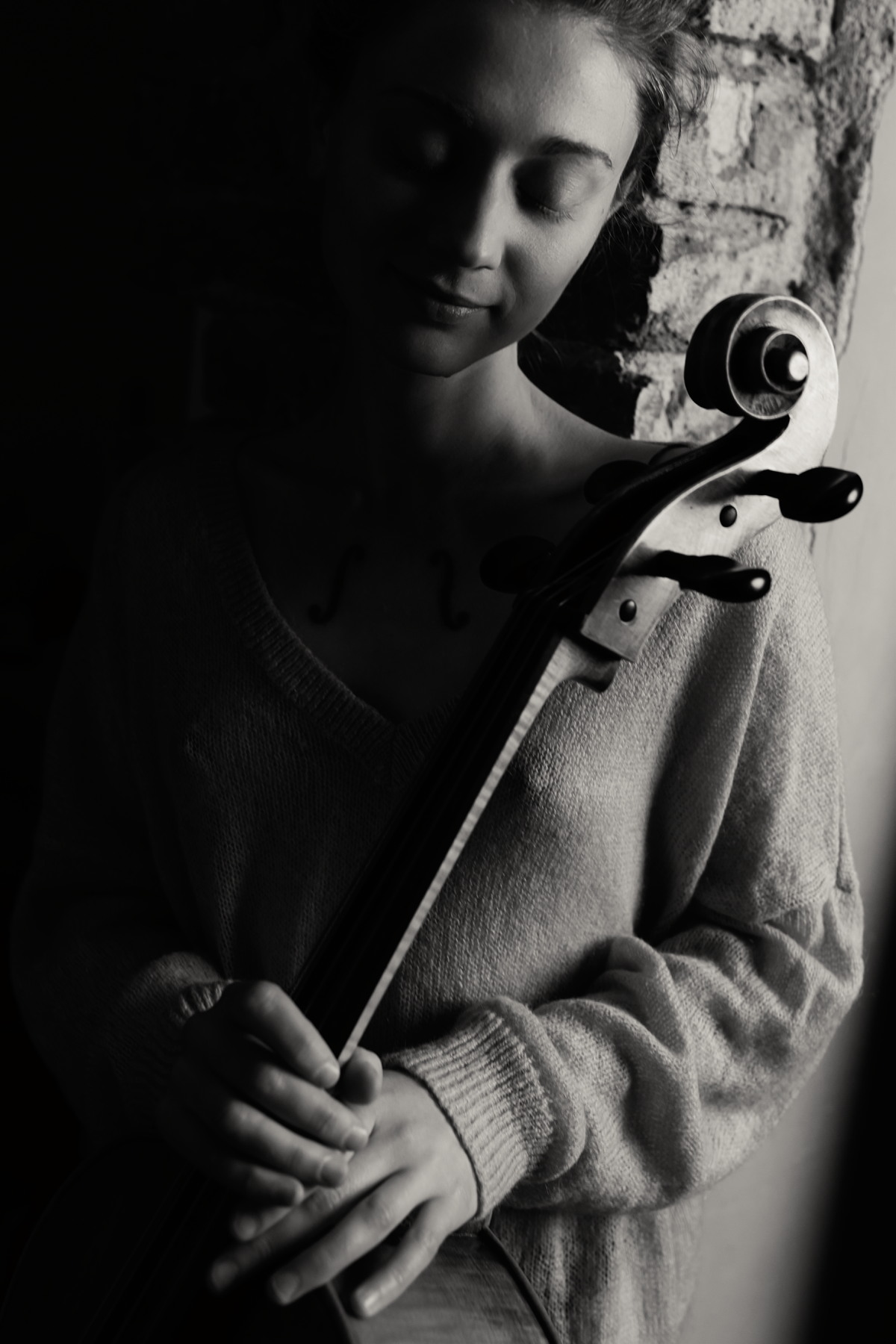Woman holding a cello in low light.