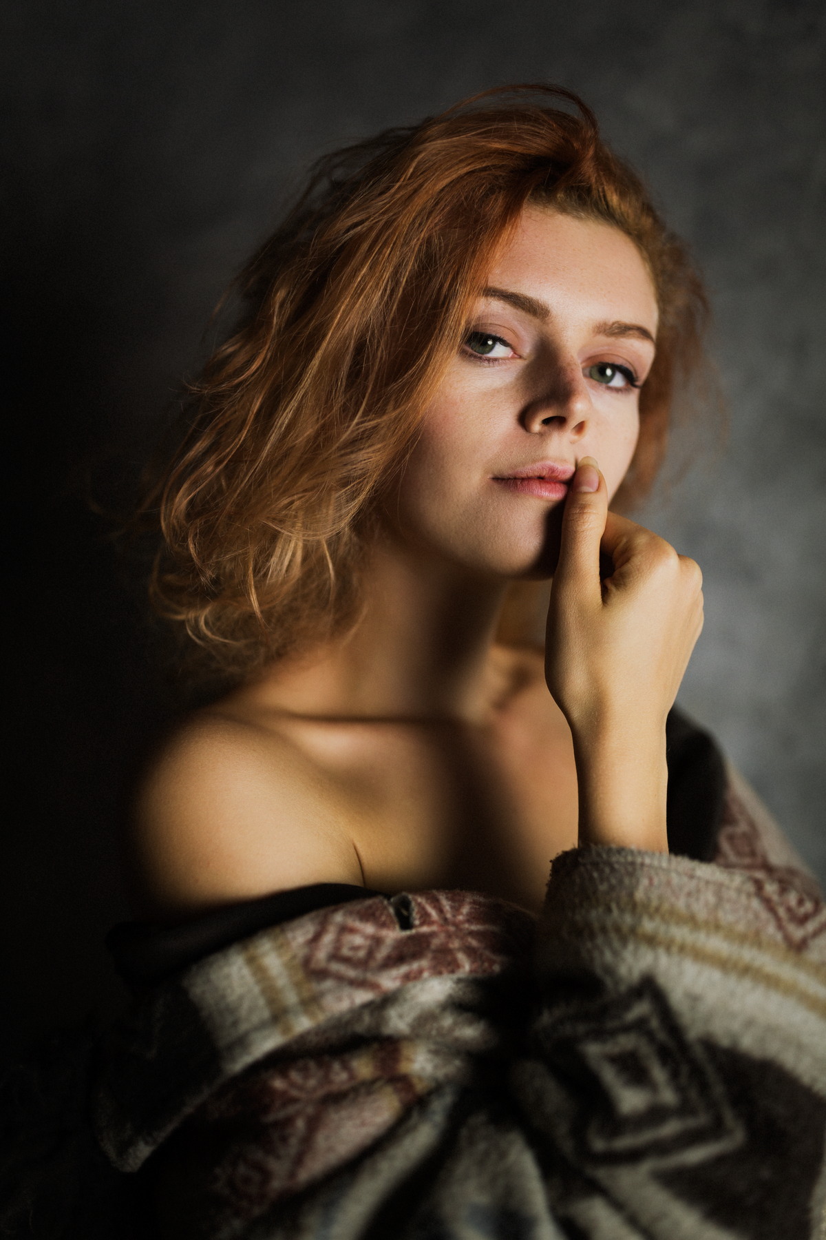 Color portrait of a red-haired woman with bare shoulders wrapped in patterned fabric.