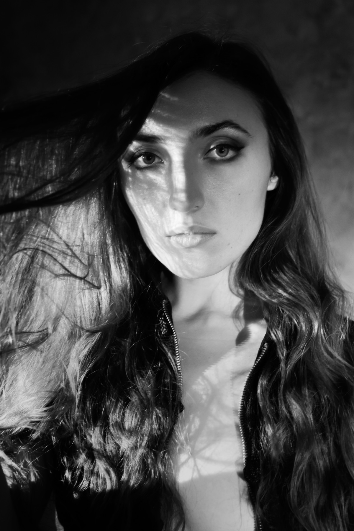 Black-and-white close portrait of a dark-haired woman under a side light.