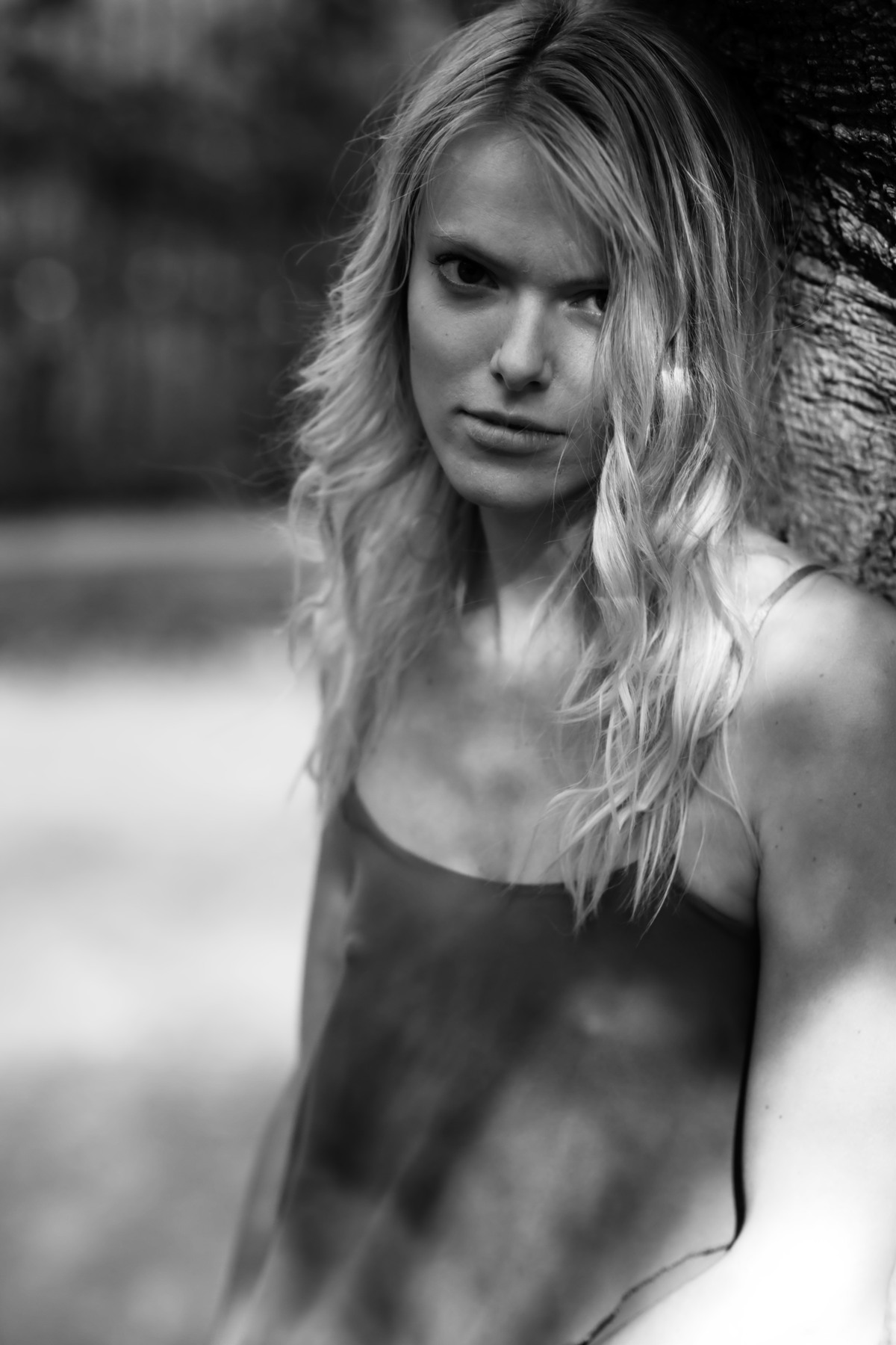 Black-and-white outdoor portrait of a blonde woman in a sleeveless dress.