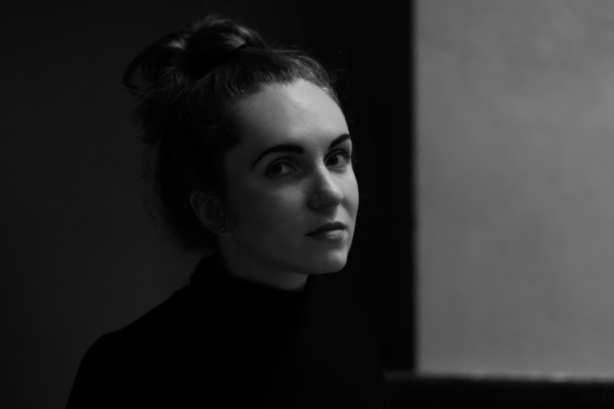 Low-key black-and-white profile portrait of a woman in a dark turtleneck.