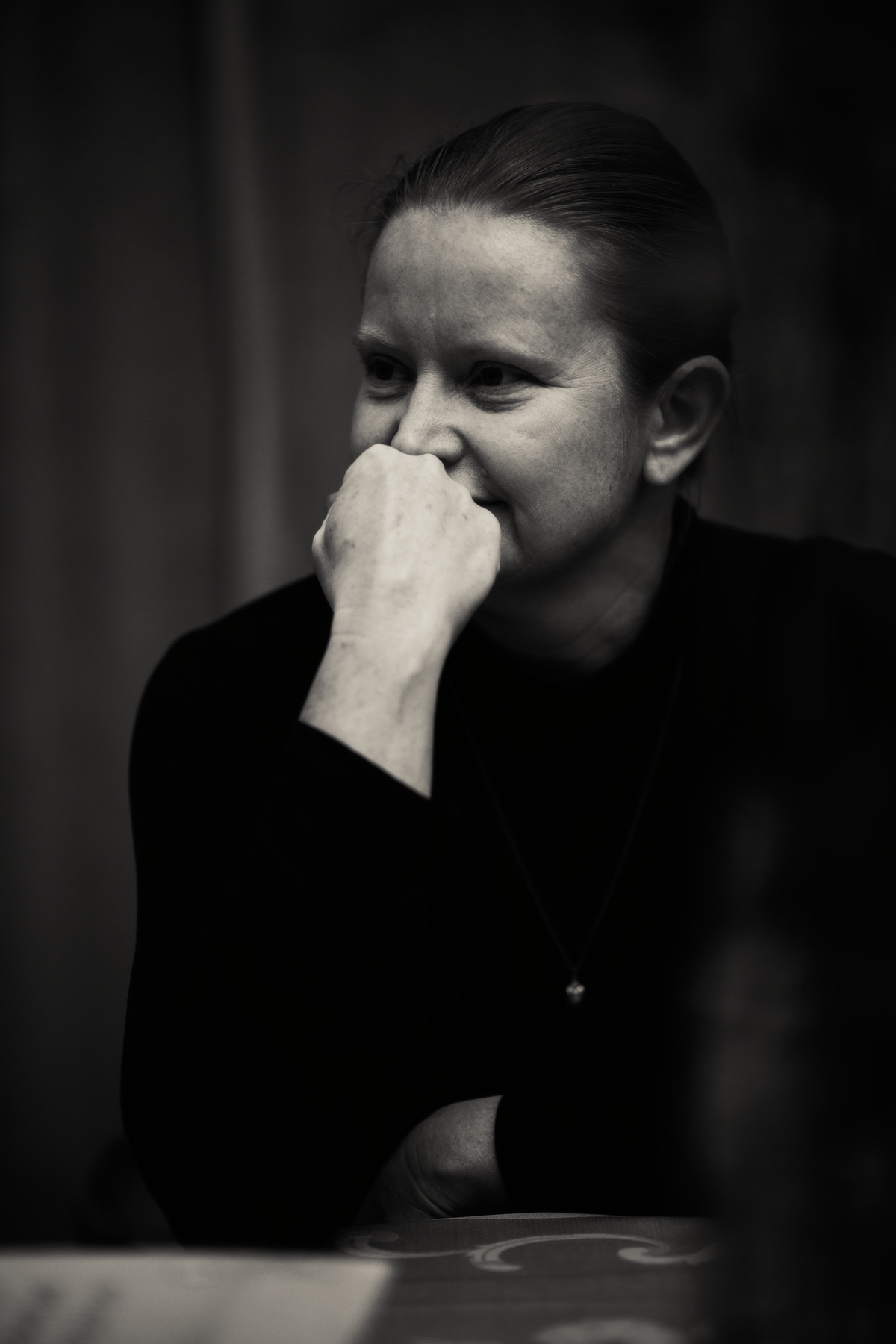 Black-and-white portrait of a seated person resting a hand against their mouth.