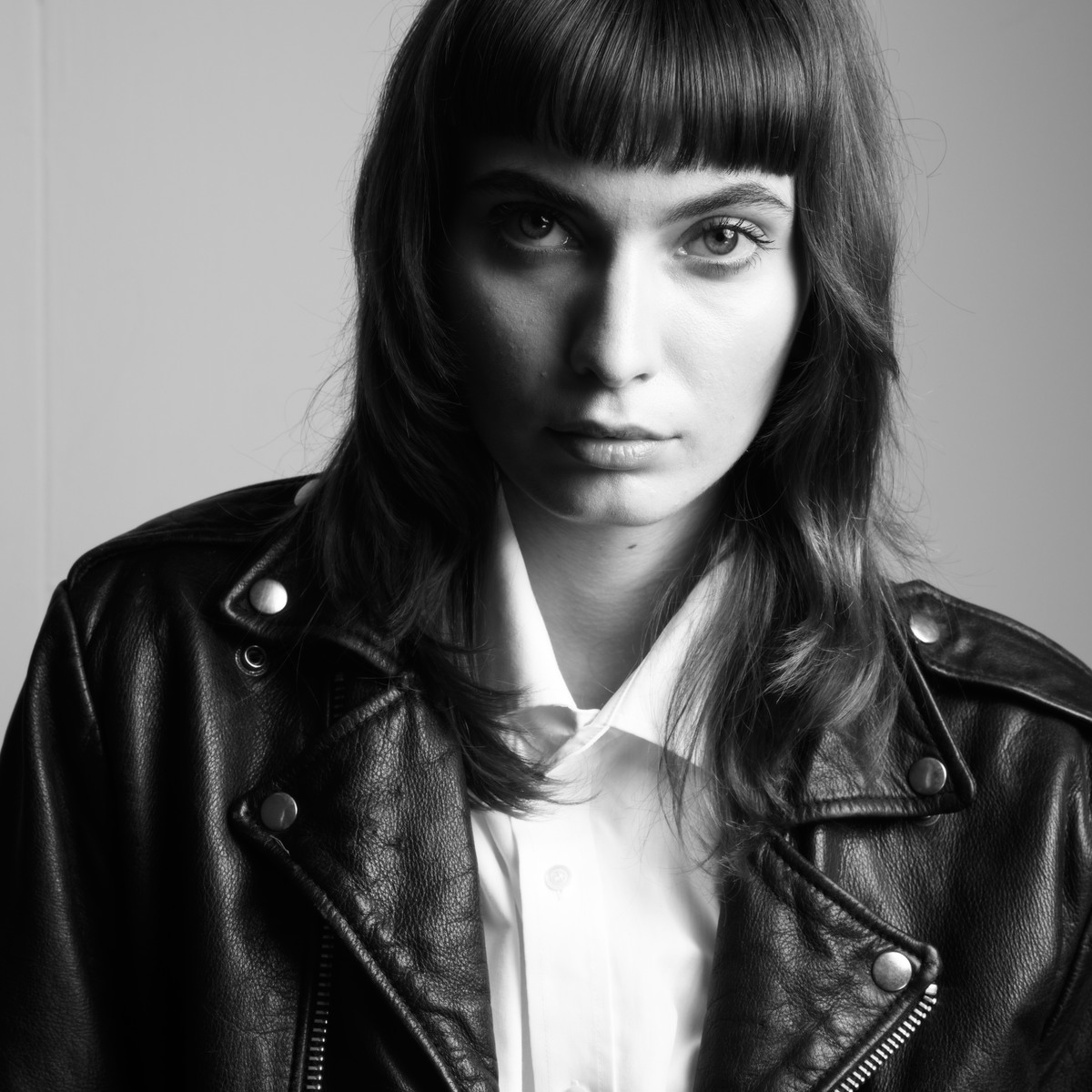 Black-and-white portrait of a woman with a blunt dark bob in a leather jacket.