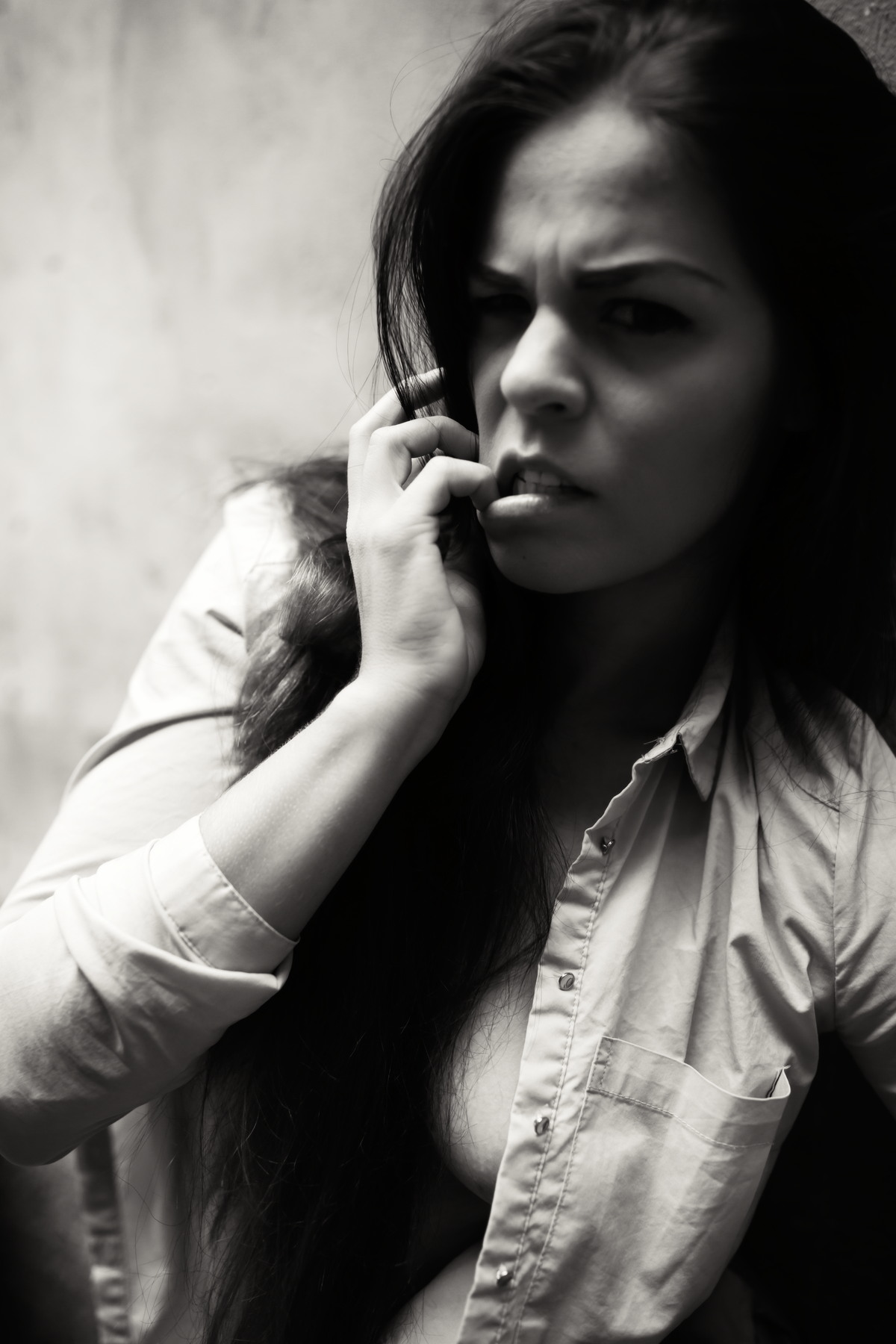 Black-and-white close portrait of a woman with a hand near her face.