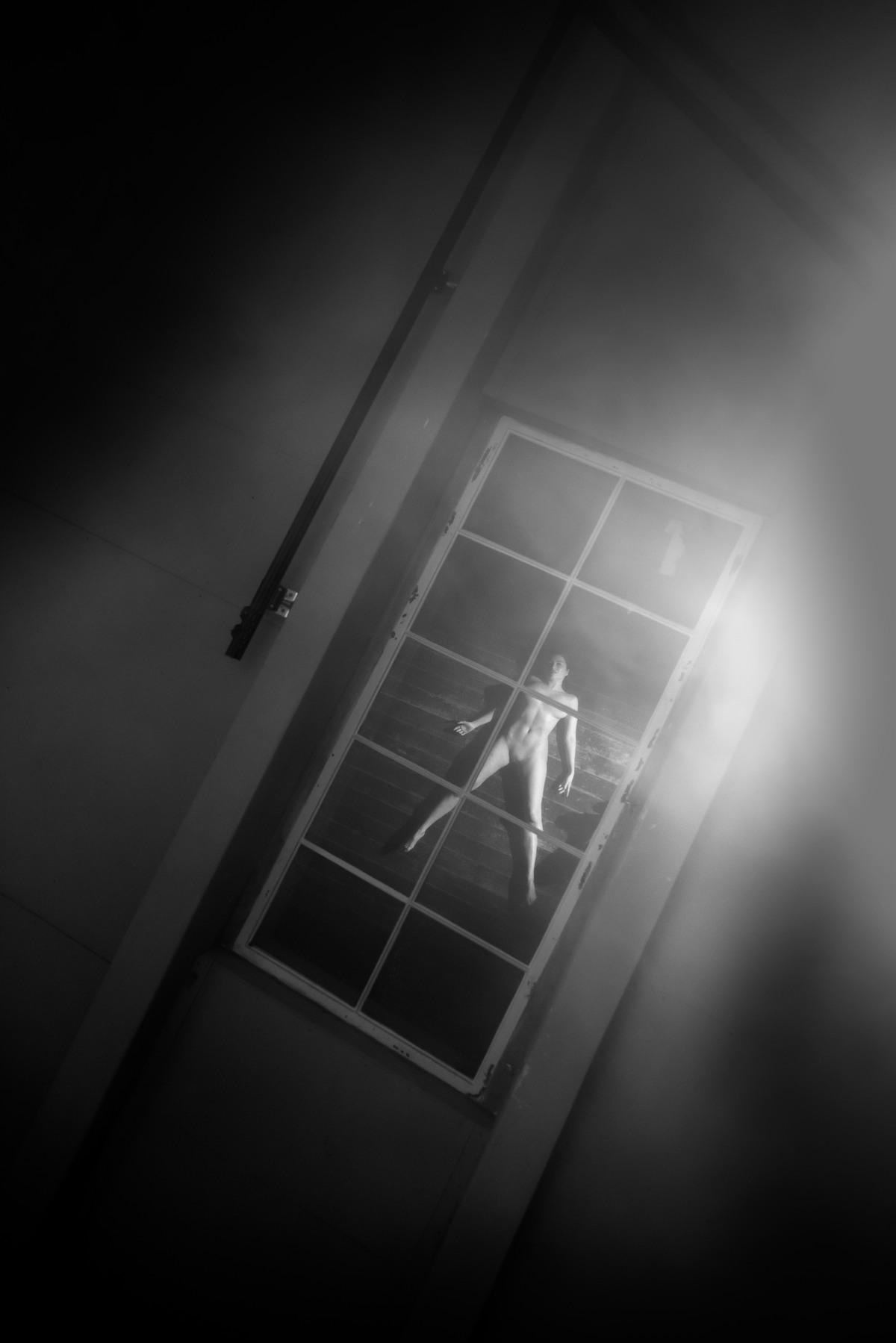 Reflection of a distant figure framed by a tilted doorway and bright light.